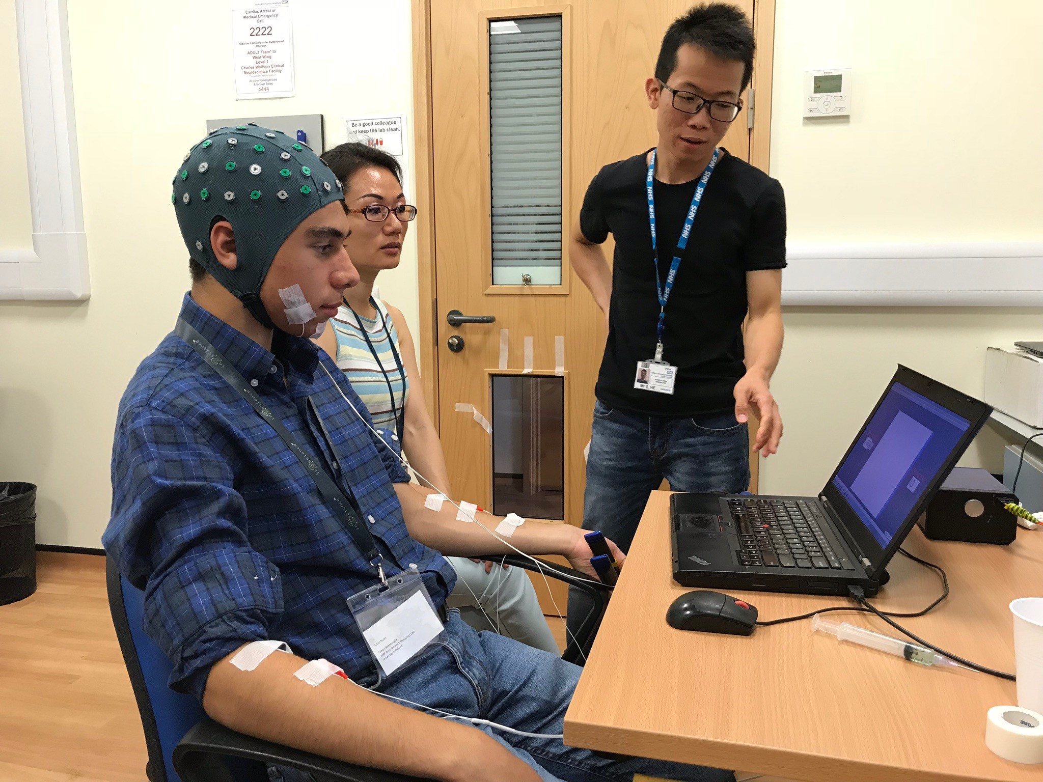 In2scienceUK student Artur records his own brain and muscle activity at the MRC BNDU, guided by Unit scientists Huiling Tan (seated) and Shenghong He.