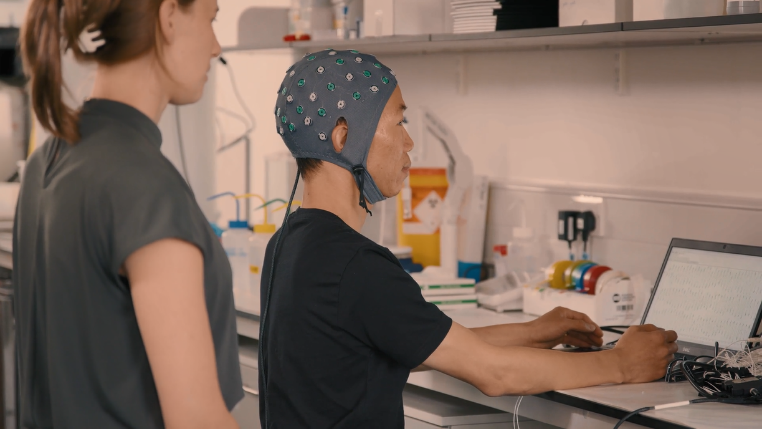 A screen shot from the video The Symphony of the Brain showing Unit researchers Demi Brizee (left) and Shenghong He (right).