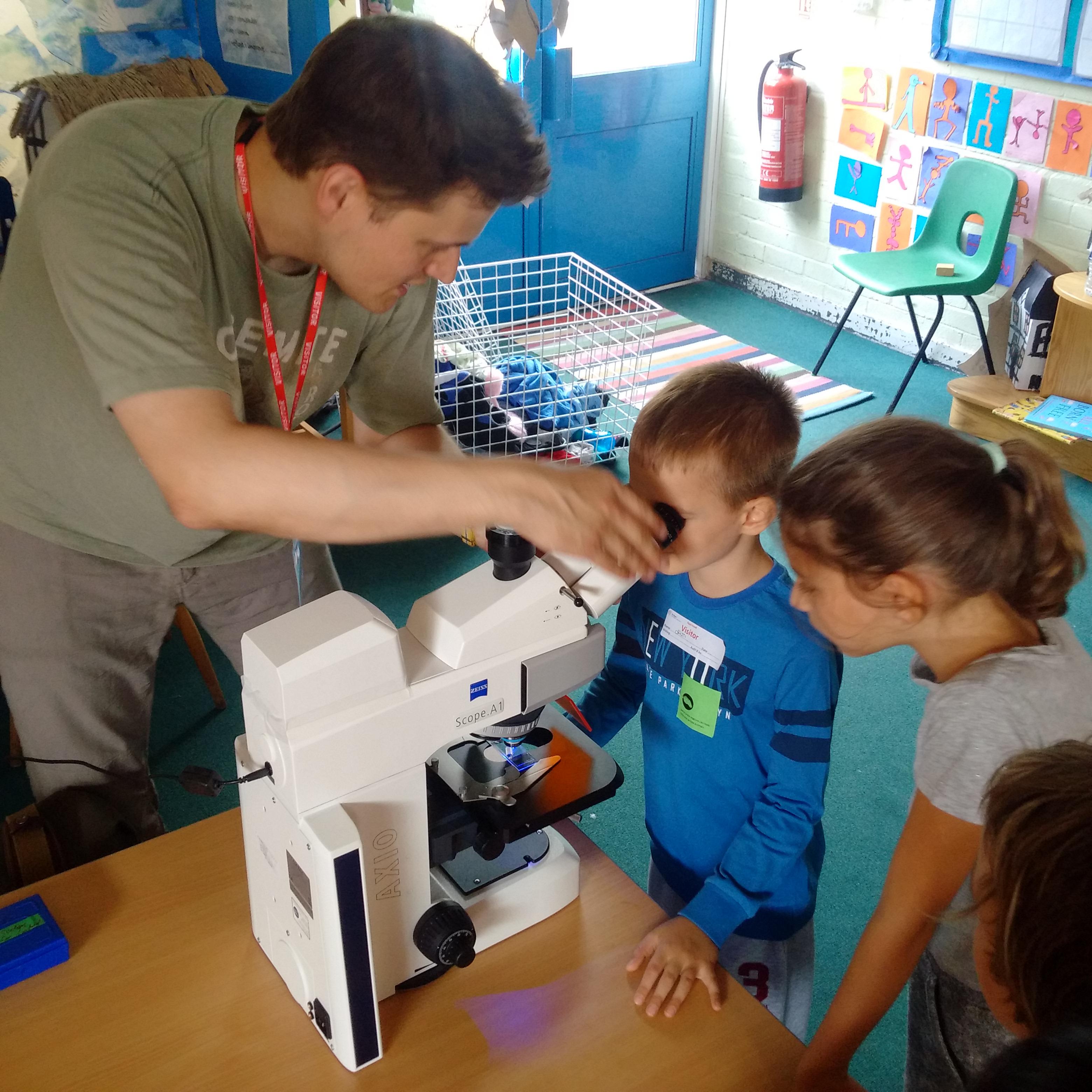 Unit scientist Ben Micklem helps pupils to look at nerve cells using one of the Unit’s fluorescence microscopes.
